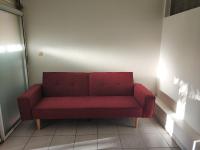 a red couch sitting in the corner of a room at Appartement d&#39;une chambre avec jardin clos et wifi a Le Lamentin in Le Lamentin
