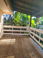 a wooden porch with a white fence and trees at Appartement d&#39;une chambre avec jardin clos et wifi a Le Lamentin in Le Lamentin