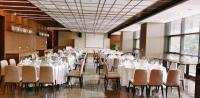 um salão de banquetes com mesas e cadeiras brancas e um ecrã em Hamps Hotel ShenZhen em Shenzhen