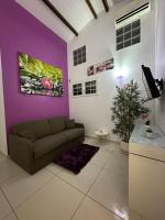 a living room with a couch and a purple wall at Appartement Coeur de Papillon in Baie-Mahault