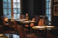 a dining room with tables and chairs and windows at Boutique Hotel KRISTOFS in Rīga