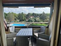 a balcony with a table and chairs and a pool at Le petit coin de Paradis in Varaville