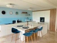 a kitchen with blue walls and a kitchen island with blue chairs at Manava Villa vue mer et Mont Saint Michel piscine intérieure in Saint-Jean-le-Thomas