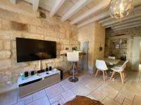 a living room with a tv on a stone wall at Bienvenue au 6 - Calme et charme de la pierre. in Fourques