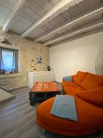 a living room with an orange couch and a ottoman at Bienvenue au 6 - Calme et charme de la pierre. in Fourques