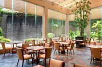 Un restaurante con mesas y sillas y grandes ventanales. en Sheraton Dongguan Hotel, en Dongguan