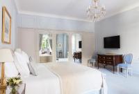 a white bedroom with a bed and a desk and a television at Le Bristol Paris - an Oetker Collection Hotel in Paris