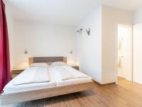 a bedroom with a bed with white walls and wooden floors at Emma Top 2 in Dienten am Hochkönig