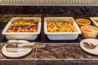 Drei Tabletts mit Essen standen auf einer Theke, dazu Teller. in der Unterkunft Best Western Click Sathorn 11 Bangkok in Bangkok