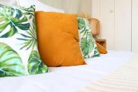 a bed with an orange pillow and tropical pillows at Un cocon face à la mer in Plérin