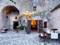 un antiguo edificio de piedra con mesas y sillas. en Sextantio Le Grotte Della Civita, en Matera
