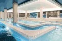 a large swimming pool with blue water in a building at Appartement Hermitage à 10 minutes de Disney in Montévrain