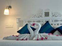 Dos cisnes hechos de toallas en una cama en Oceanic - Luxury Boutique Hotel, en Palolem