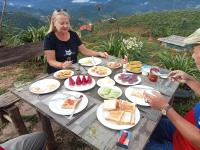 una mujer sentada en una mesa con platos de comida en A Su Homestay Mù Cang Chải, en Mù Cang Chải