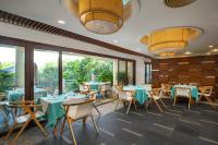 a restaurant with tables and chairs and large windows at Sunshine Resort Intime Sanya in Sanya
