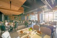 een eetkamer met tafels en stoelen en ramen bij The Code Hotel & Spa Da Nang - Complimentary Daily Afternoon Tea in Sky Bar in Da Nang