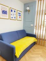 a blue couch with a yellow blanket on it at Chez les deux garçons in Montrouge