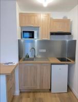 a kitchen with wooden cabinets and a sink and a microwave at Prochain Arrêt : Disneyland in Montévrain