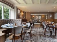 ein Restaurant mit Tischen und Stühlen und einer Couch in der Unterkunft Delta Hotels by Marriott Worsley Park Country Club in Worsley