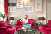 a woman sitting on a red couch in a living room at Best Western Hotel Lakmi Nice in Nice