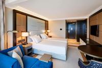 a bedroom with a large white bed and a blue couch at Hilton Budapest in Budapest