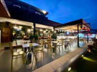 Un patio al aire libre con mesas y sillas por la noche. en The Bridge Residence Hotel, en Kanchanaburi