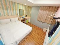 a room with a bed and a desk and a television at Sanduo Hotel in Kaohsiung