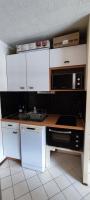 a kitchen with white cabinets and a microwave at Appart 4-6 pers au pied des pistes toutes saisons in Molines-en-Queyras