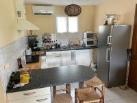 a kitchen with a refrigerator and a table with chairs at Gîte ylangylang in Saint-Paul-le-Jeune