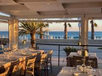 een restaurant met tafels en stoelen en de oceaan bij Villa Salisà in Menfi