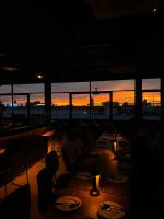a group of people sitting at a table in a restaurant at sunset at C'HOUSE Bangkok in Pom Prap