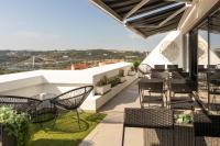 a patio with chairs and tables on a roof at Penedo da Saudade Suites &amp; Hostel in Coimbra