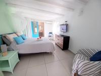 a bedroom with a bed and a dresser and a television at La Rose du Bresil Marie-Galante in Capesterre