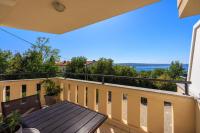a balcony with a wooden table and a view of the ocean at Apartments Petak Novi in Dramalj