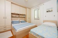 a bedroom with two beds and a cabinet at Apartments Petak Novi in Dramalj
