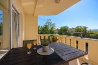 a table on a balcony with two glasses of wine at Apartments Petak Novi in Dramalj