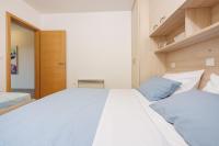 a bedroom with a large white bed with blue pillows at Apartments Petak Novi in Dramalj