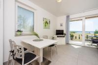 a white dining room with a white table and chairs at Apartments Petak Novi in Dramalj