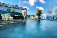 a woman is standing next to a swimming pool at Dylan Hotel Danang in Da Nang