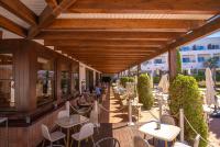 an outdoor patio with tables and chairs and people sitting at tables at Hotel Fuerte Conil-Resort in Conil de la Frontera