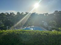 a view of a swimming pool with the sun shining at Appartement Coeur de Papillon in Baie-Mahault