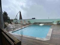 a swimming pool on a deck with chairs and an umbrella at Villa Bois Court 3 chambres in Le Tampon