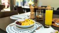 Una mesa con un tazón de comida y un vaso de jugo de naranja. en Windhoek Gardens Boutique Hotel, en Windhoek