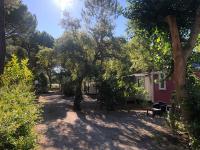 a red house with trees and a bench in front of it at Mobile home 5-pers Camping Leï Suves-Côtes d&#39;Azur-including airco in Roquebrune-sur-Argens
