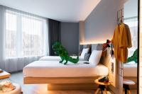 a dinosaur toy sitting on a bed in a bedroom at Moxy The Hague in The Hague