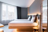 a bedroom with two beds and a large window at Moxy The Hague in The Hague