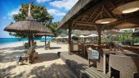um restaurante na praia com cadeiras e guarda-sóis em Hilton Mauritius Resort & Spa em Flic-en-Flac