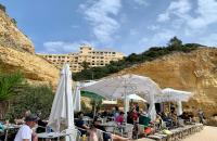 een groep mensen die aan tafels met paraplu's zitten bij Ver-O-Mar in Carvoeiro