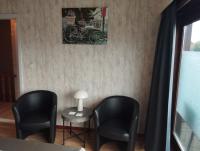 a room with two black chairs and a table and a lamp at Logies Lily in Oudenburg