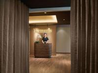 a woman is standing at a counter in a lobby at Hotel de l'Opera Hanoi - MGallery in Hanoi